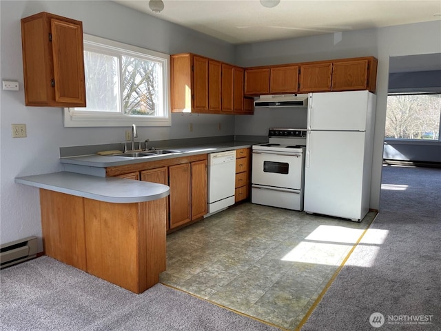 kitchen with white appliances, brown cabinetry, a peninsula, under cabinet range hood, and a sink