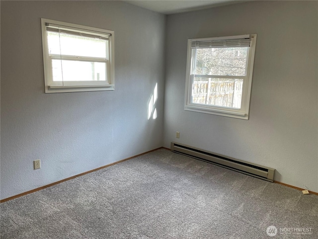 unfurnished room featuring a baseboard heating unit, carpet, a wealth of natural light, and baseboards