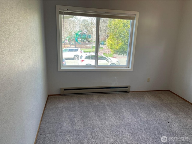 carpeted spare room with a baseboard radiator and a textured wall