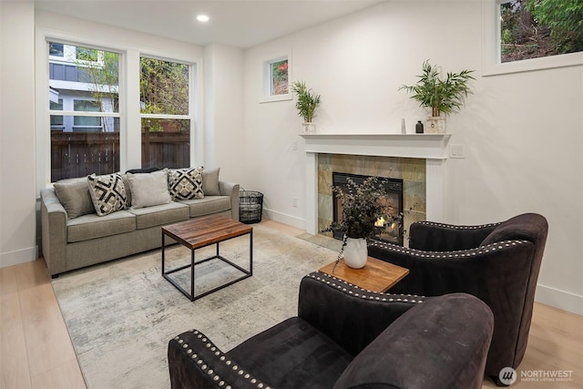 living area with baseboards, a tiled fireplace, wood finished floors, and recessed lighting