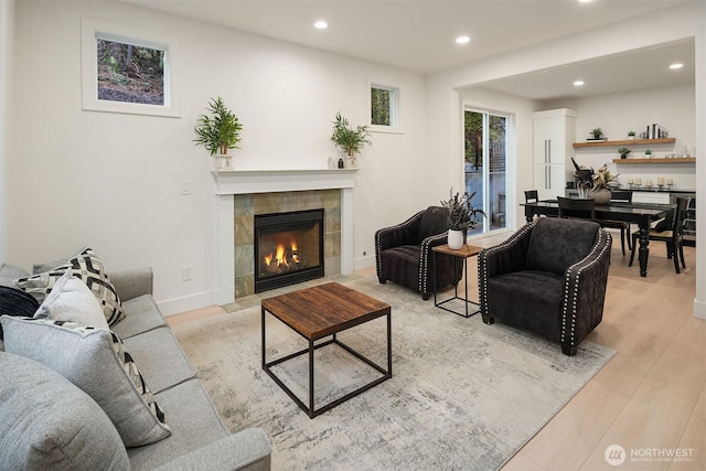 living room featuring recessed lighting, a fireplace, light wood-style flooring, and baseboards