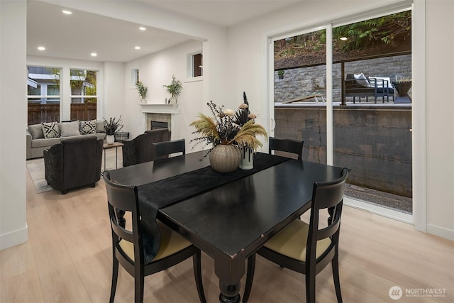 dining area with a fireplace, light wood-style flooring, and recessed lighting