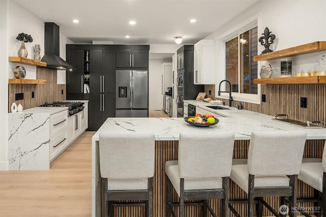 kitchen featuring stainless steel fridge with ice dispenser, wall chimney exhaust hood, gas stovetop, open shelves, and a sink