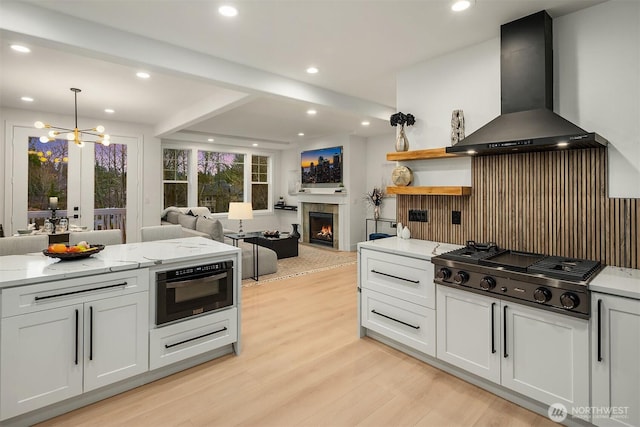 kitchen featuring a warm lit fireplace, extractor fan, appliances with stainless steel finishes, open shelves, and light wood finished floors