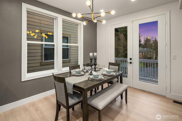 dining room featuring an inviting chandelier, light wood-style flooring, visible vents, and baseboards