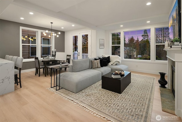 living area featuring light wood-type flooring, a fireplace, a notable chandelier, and recessed lighting