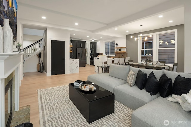 living room featuring a chandelier, light wood finished floors, stairway, and recessed lighting