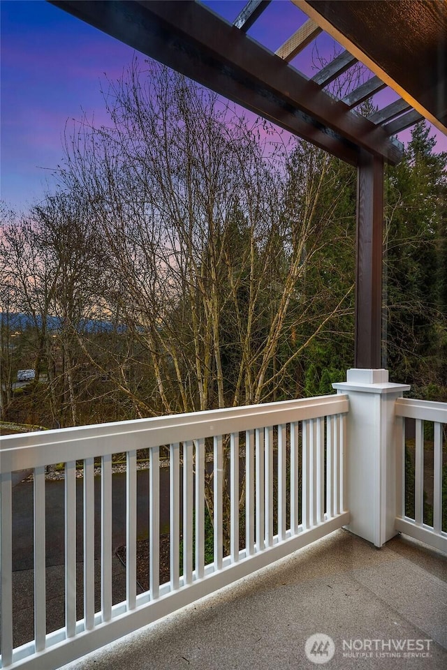 balcony at dusk featuring a pergola