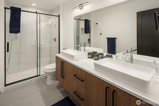 full bathroom featuring double vanity, a stall shower, toilet, tile patterned flooring, and a sink