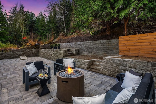 patio terrace at dusk with an outdoor living space with a fire pit