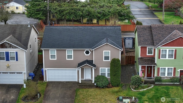 view of front of home featuring driveway, an attached garage, fence, and a front yard