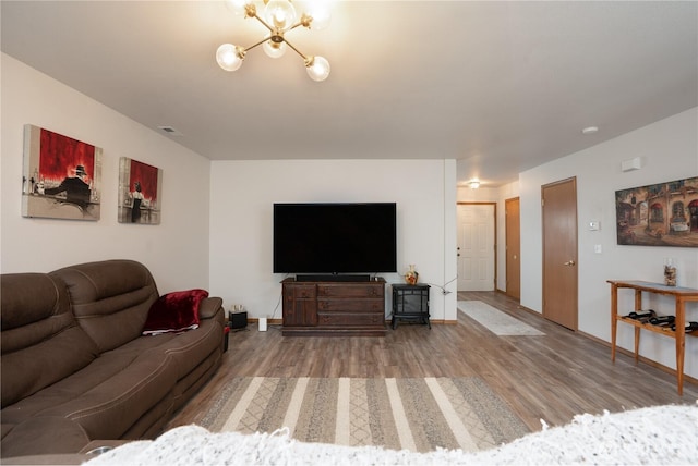 living room with visible vents, baseboards, a chandelier, and wood finished floors