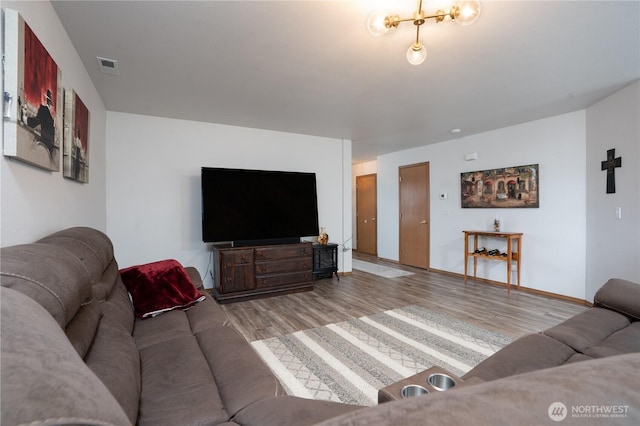 living area with baseboards, visible vents, and wood finished floors