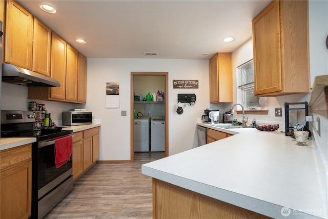 kitchen featuring visible vents, appliances with stainless steel finishes, under cabinet range hood, a sink, and washing machine and dryer