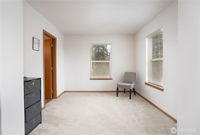 sitting room with baseboards and light colored carpet
