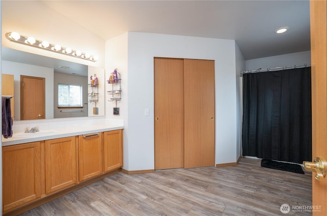 bathroom with baseboards, wood finished floors, and vanity