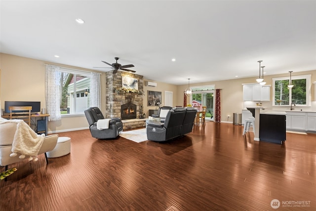 living area featuring recessed lighting, dark wood-style flooring, a fireplace, a ceiling fan, and baseboards