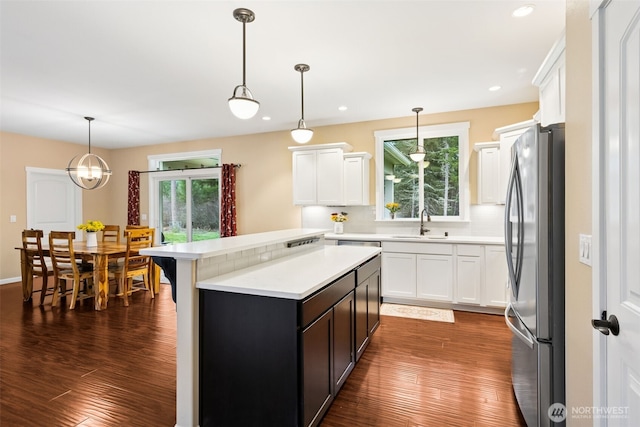 kitchen featuring freestanding refrigerator, a healthy amount of sunlight, light countertops, and white cabinetry