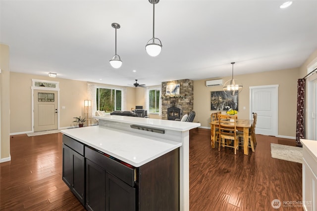 kitchen with dark wood finished floors, light countertops, open floor plan, a stone fireplace, and a wall mounted air conditioner