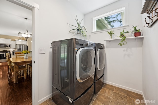 laundry room featuring laundry area, washer and clothes dryer, baseboards, and an inviting chandelier