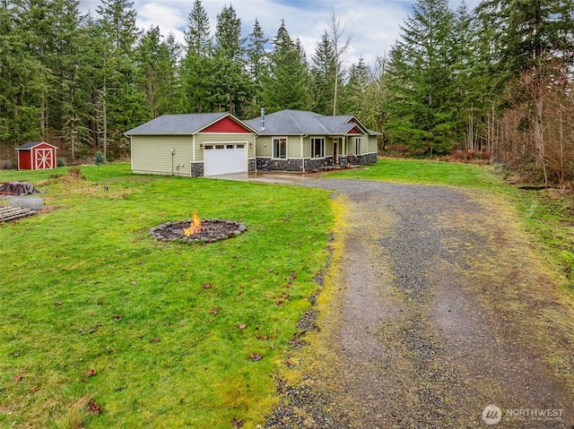 ranch-style house with a storage unit, an outdoor fire pit, stone siding, driveway, and a front lawn