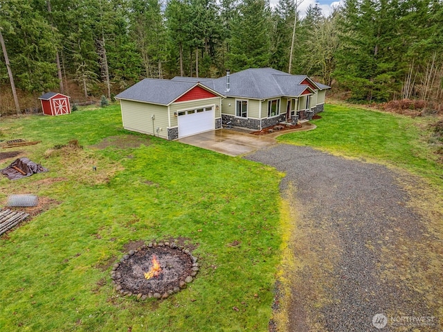 view of front of property with aphalt driveway, an attached garage, stone siding, a forest view, and a shed