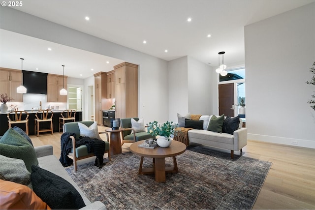 living room featuring light wood-type flooring, baseboards, and recessed lighting