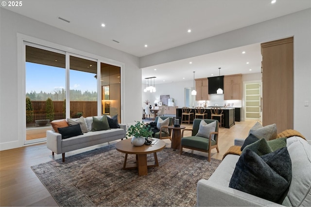 living area with light wood-style flooring, visible vents, baseboards, and recessed lighting