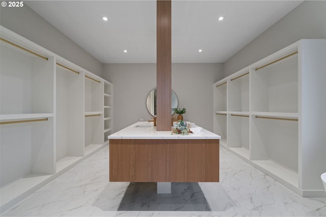 walk in closet featuring marble finish floor and a sink