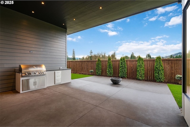 view of patio featuring a fenced backyard, a fire pit, and area for grilling