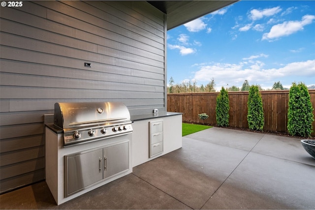 view of patio / terrace with an outdoor kitchen, a grill, and fence