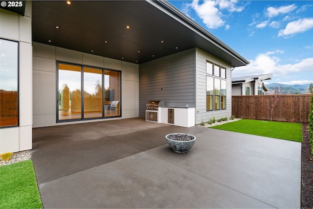 back of house featuring a patio, a yard, an outdoor kitchen, and fence