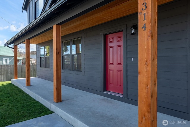 doorway to property with fence and a porch