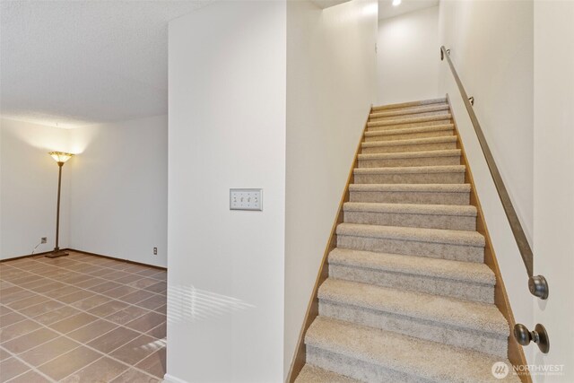 stairs featuring a textured ceiling, baseboards, and tile patterned floors