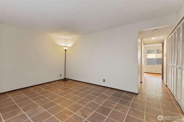 unfurnished room featuring a textured ceiling and tile patterned floors