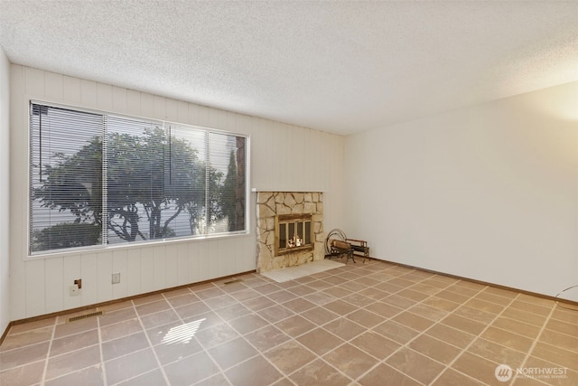 unfurnished living room with a fireplace, visible vents, and a textured ceiling