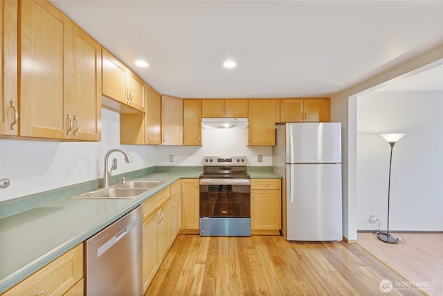 kitchen with light wood finished floors, light brown cabinetry, appliances with stainless steel finishes, a sink, and under cabinet range hood