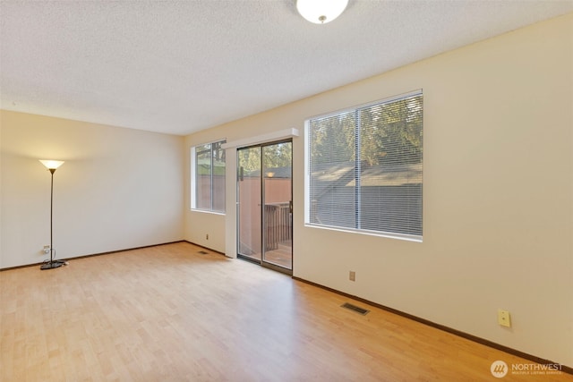 unfurnished room featuring a textured ceiling, visible vents, and wood finished floors