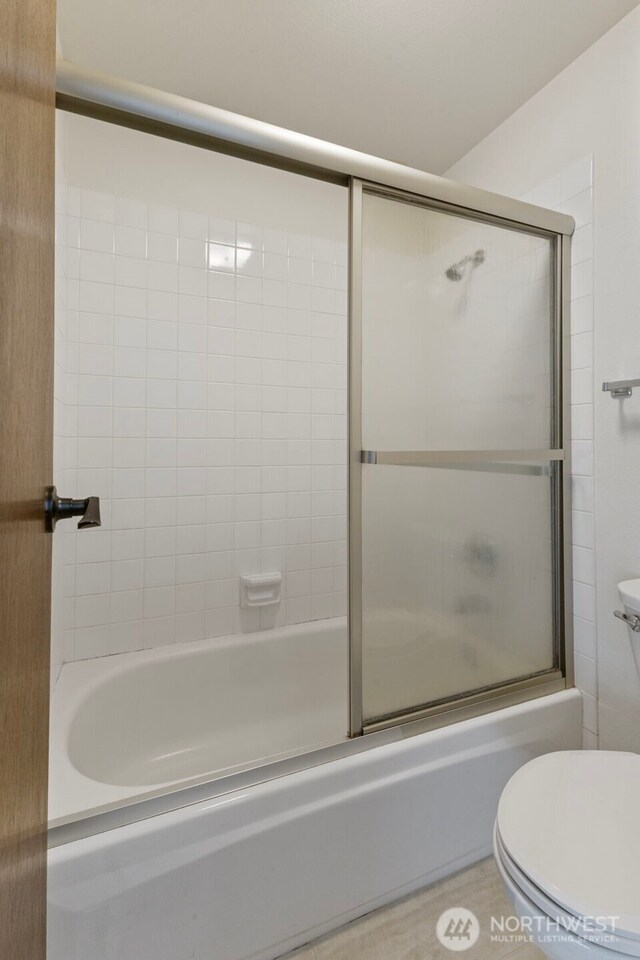 bathroom with shower / bath combination with glass door and toilet