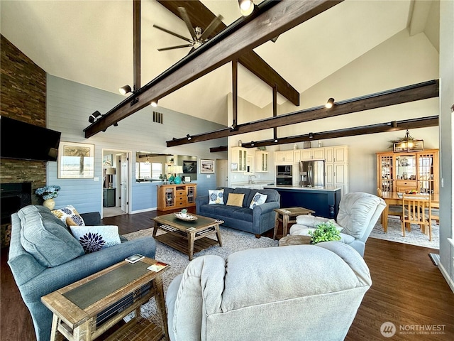 living area with dark wood-type flooring, ceiling fan, beamed ceiling, a fireplace, and high vaulted ceiling