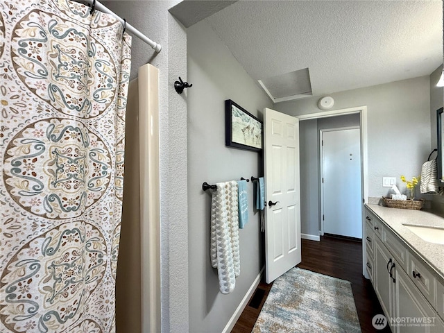 full bath featuring vanity, wood finished floors, baseboards, a textured ceiling, and curtained shower