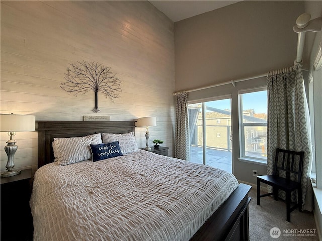 carpeted bedroom with a high ceiling and access to exterior