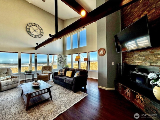 living room with a fireplace, wood finished floors, baseboards, and a towering ceiling