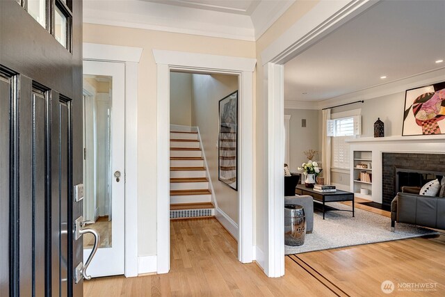 interior space featuring baseboards, stairs, light wood-style floors, and ornamental molding