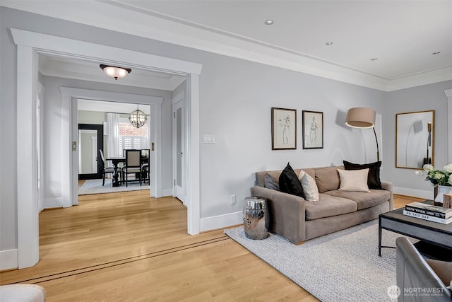 living room with light wood finished floors, a notable chandelier, baseboards, and ornamental molding