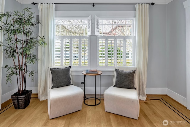 living area with a wealth of natural light, baseboards, and wood finished floors