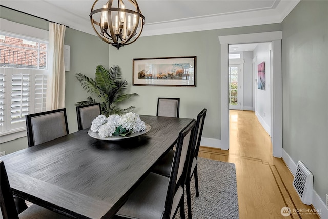 dining room featuring an inviting chandelier, crown molding, baseboards, and light wood finished floors