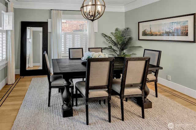 dining area with a chandelier, light wood finished floors, baseboards, and ornamental molding