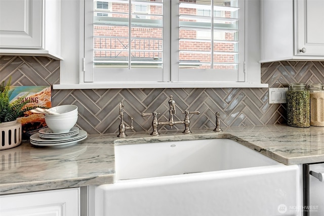 room details featuring tasteful backsplash, white cabinetry, and a sink