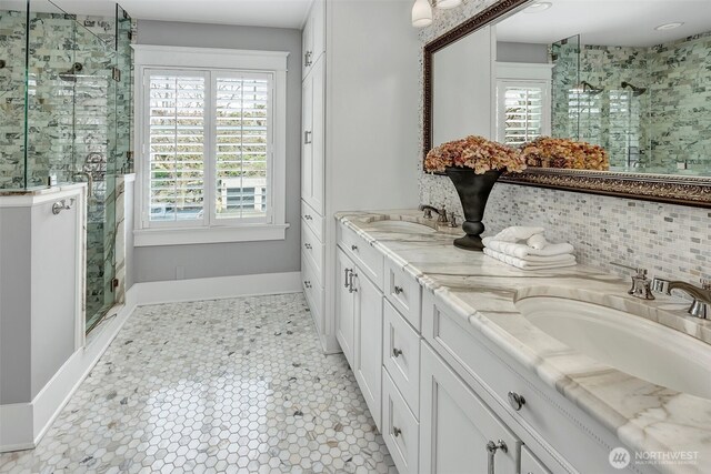 bathroom featuring double vanity, a stall shower, and a sink